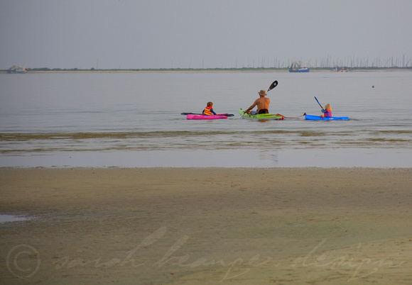 A father kayaks with his children off of East Beach